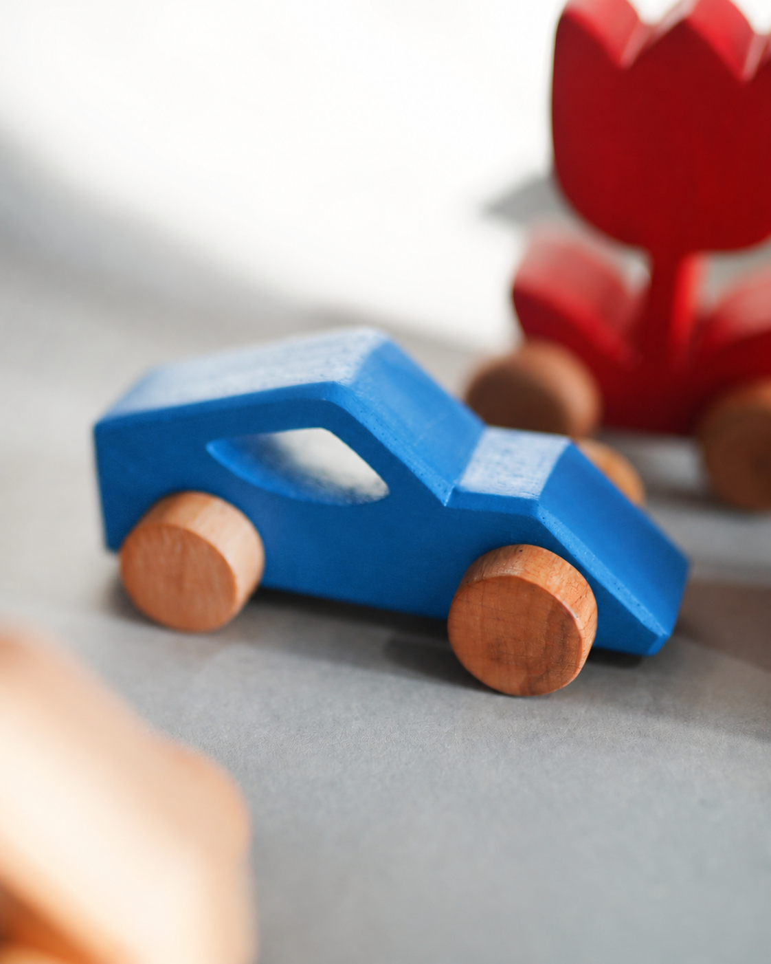 Blue Drift Wooden Car in soft daylight with red Tulip in the background